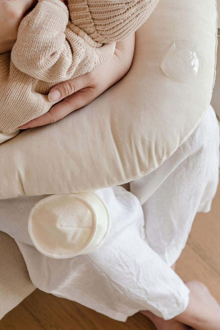 A woman is breastfeeding her baby on a couch.