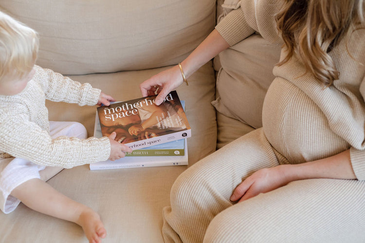 A pregnant woman reading a book to her child.