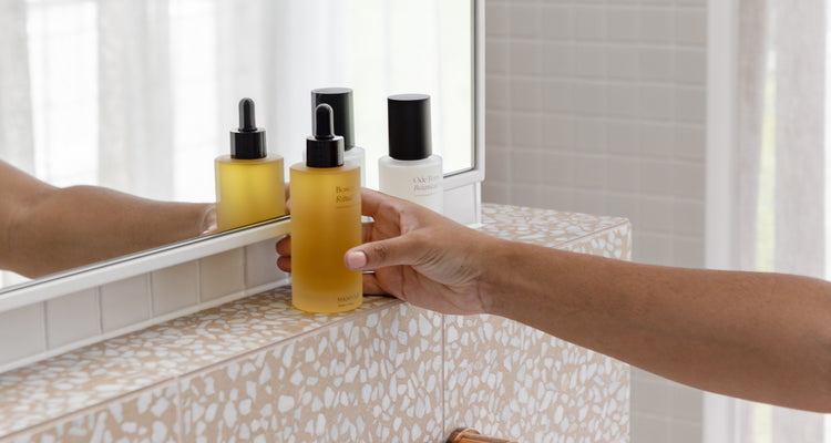 A person holding a bottle of oil in front of a mirror.