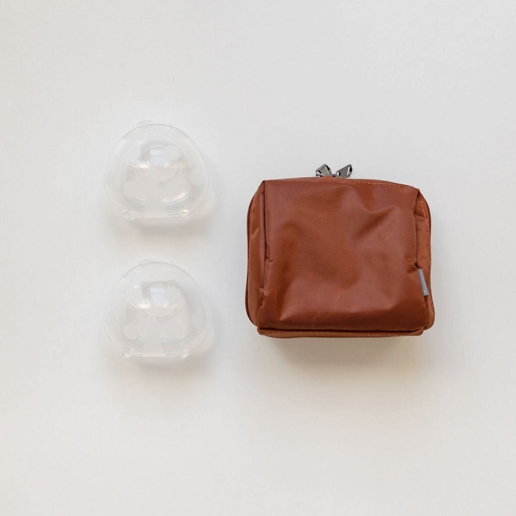 A brown storage bag with two Haakaa Ladybug silicone Breast Milk Collectors.