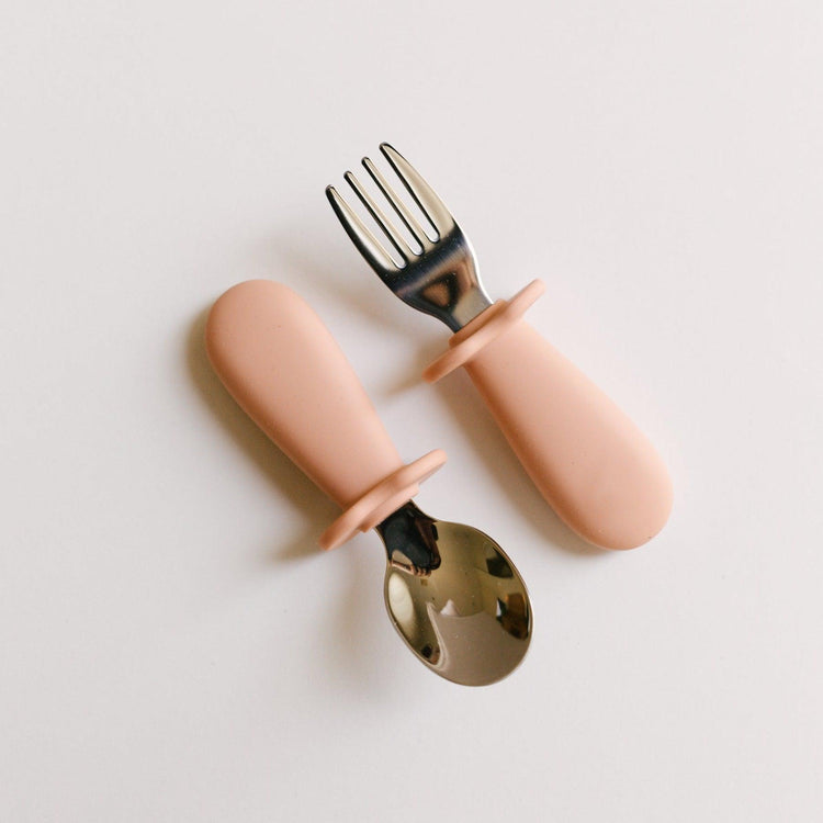 Two Rommer melon toddler cutlery sets on a white surface.