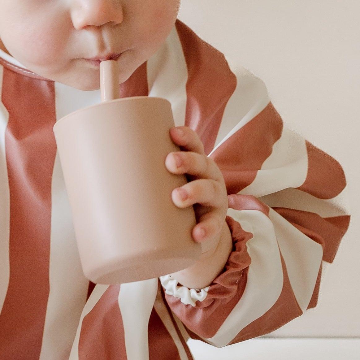 A baby in a striped shirt drinking from a Rommer premium silicone sippy cups | 2pk.